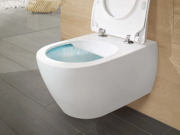 A modern wall-mounted toilet with an open lid is shown in a light, minimalist bathroom with wooden accents.