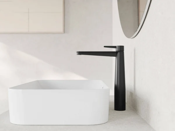 Conum Waschbeckenarmatur in weißem Badezimmer Ein minimalistisches Badezimmer-Waschbecken mit einem rechteckigen weißen Becken und einem hohen, schwarzen Wasserhahn, der an einer beigen Arbeitsplatte befestigt ist.