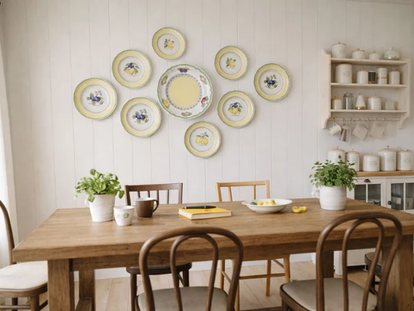 french garden plates on a wall as art A cozy dining area features a wooden table with potted plants and a notebook. Decorative plates with fruit designs hang on a white paneled wall, creating a warm, inviting atmosphere.