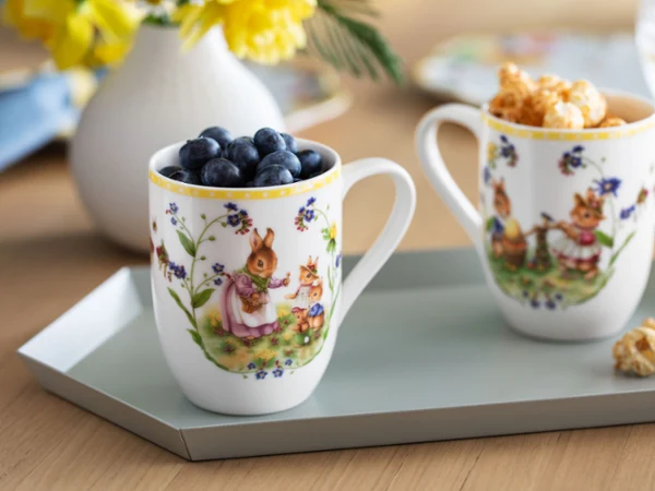 Dos tazas decorativas Spring Awakening con arándanos y palomitas en una bandeja con flores amarillas de fondo.