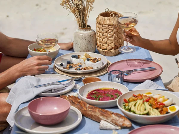 Table set with Perlemor tableware and vase A couple sitting at a table on the beach with plates from the like. by Villeroy & Boch Perlemor collection.