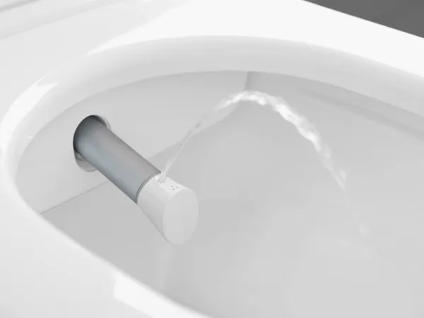 ViClean Dusch-WC Düse Nahaufnahme einer Bidetdüse, die Wasser in eine Toilettenschüssel sprüht. Die Düse ragt seitlich aus dem Toilettenrand heraus.