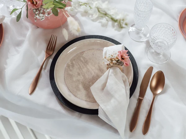 Table set with Manufacture and Perlemor plates Table decoration with a Villeroy & Boch beige Perlemor dinner plate, copper-coloured Manufacture cutlery and flowers.