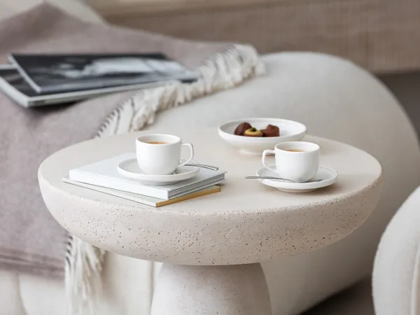 Des tasses à expresso Afina avec des chocolats sur une table basse Deux élégantes tasses à expresso Afina sur une table ronde avec un magazine et une assiette de chocolats.