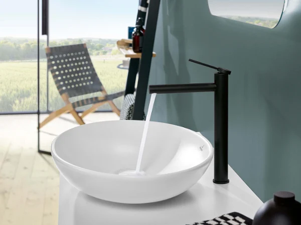 Biała umywalka Loop & Friends z baterią Biała umywalka stojąca na blacie Loop & Friends w łazience z krajobrazem w tle