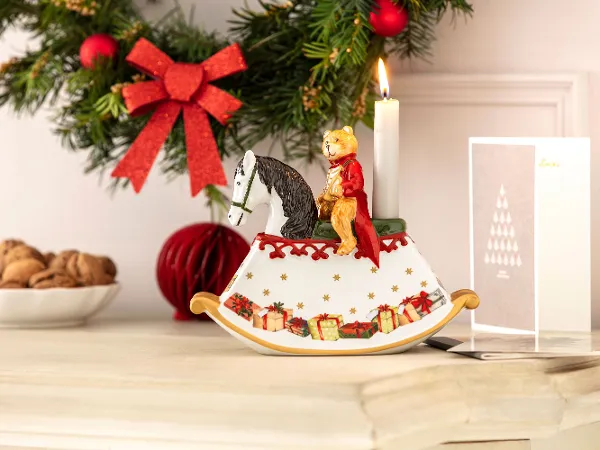 Un cheval à bascule Christmas Toy's de Villeroy & Boch sur un buffet Un buffet festif avec un cheval à bascule Christmas Toy’s, une carte de Noël et une coupe contenant des noix.