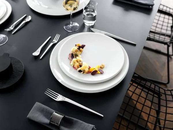 NewMoon plate with wine glasses Elegant dining table setting with NewMoon plates and wine glasses.