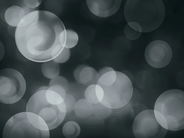 Abstract image of blurred, overlapping circles of light in shades of grey on a dark background. Abstract image of blurred, overlapping circles of light in shades of grey on a dark background.