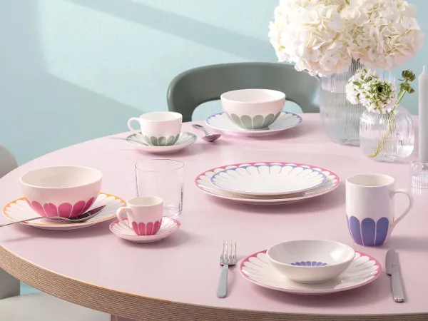 A round table set with Villeroy & Boch Fleur A round table setting with plates, mugs, cups, cutlery, glasses and white flower vases from Villeroy & Boch Fleur.