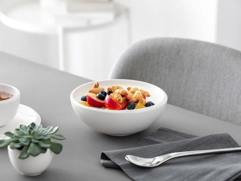 A healthy breakfast consisting of yoghurt with mixed berries and muesli, served in a white NewMoon bowl.