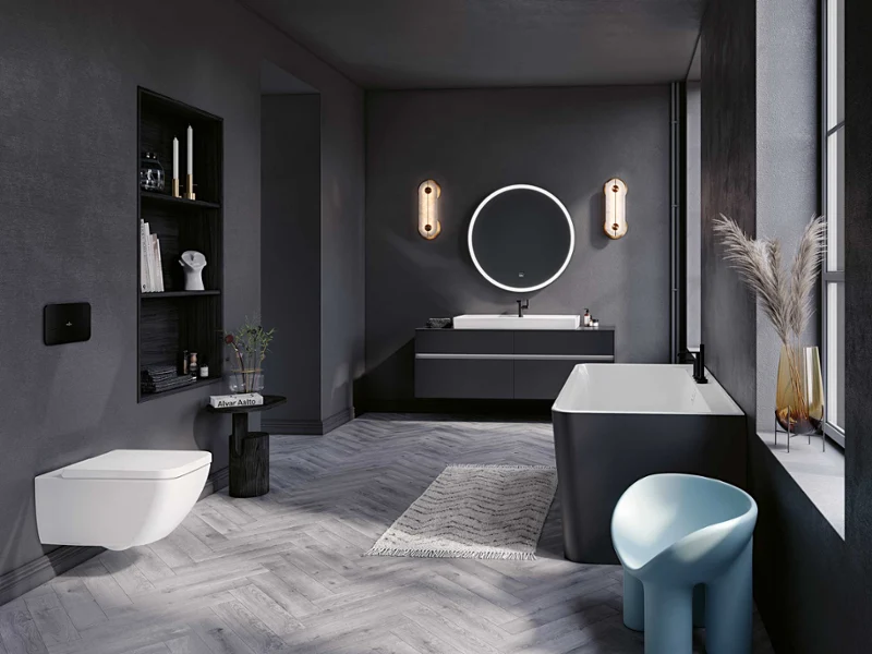 White toilet from the Collaro collection A modern bathroom with a Villeroy & Boch white wall-mounted toilet, a dark shelf with decorations and a small side table with a plant. The room has grey walls and a floor with a herringbone pattern.