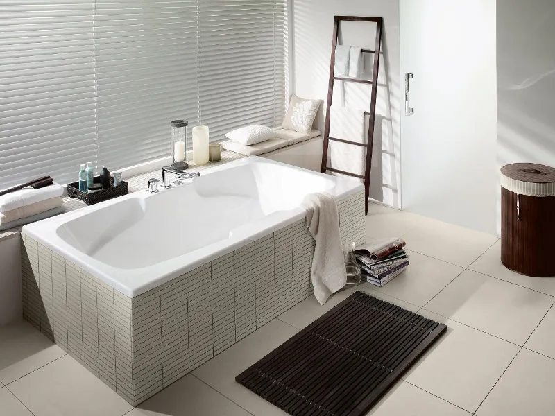 A white Colorado bath in a beige bathroom by Villeroy & Boch with a decorated window sill.