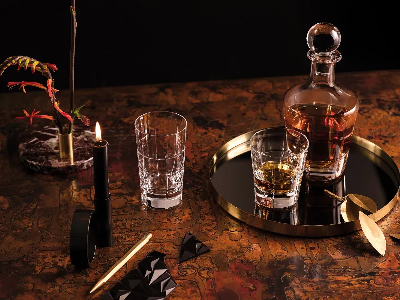 An Ardmore Club whisky decanter and glasses on a tray, next to a lit candle.