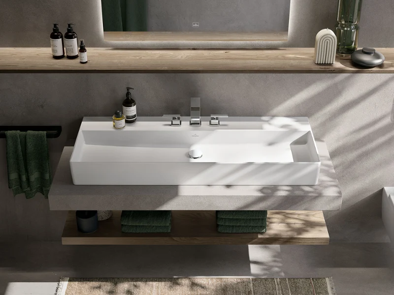 Rechteckiger Waschtisch in Stone White auf Betonkonsole mit Holzablage Memento 2.0 Waschtisch in Stone White mit präzisen Konturen und puristischem Design, eingebettet in ein modernes Bad mit natürlichen Akzenten.