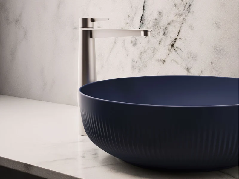 Modern matte blue countertop washbasin with an elegant silver faucet on a marble countertop.