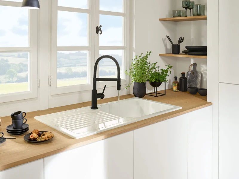 Black Linara kitchen tap in front of a window A Linara kitchen tap in front of a window with a view of the countryside