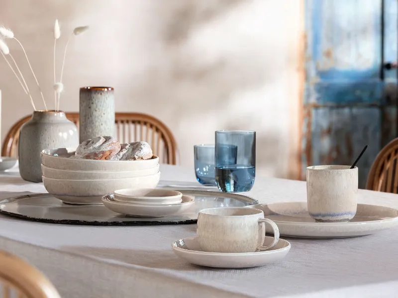 A dining table set with blue glasses from like. Glass and white tableware from the Perlemor collection.