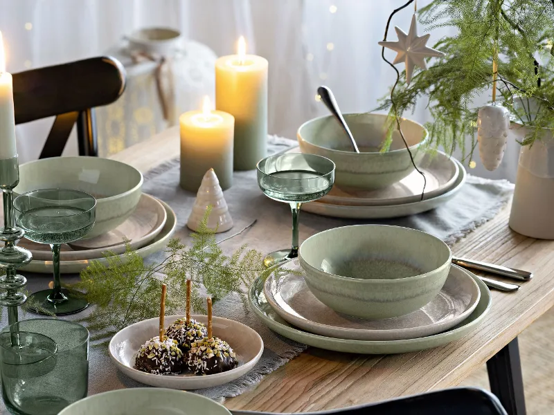 Festive table with green and beige Perlemor plates, surrounded by Winter Glow candleholders and Like glasses.