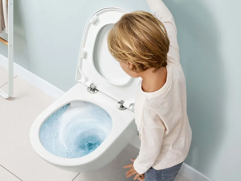 A little boy standing next to a Subway 3.0 toilet with TwistFlush technology.