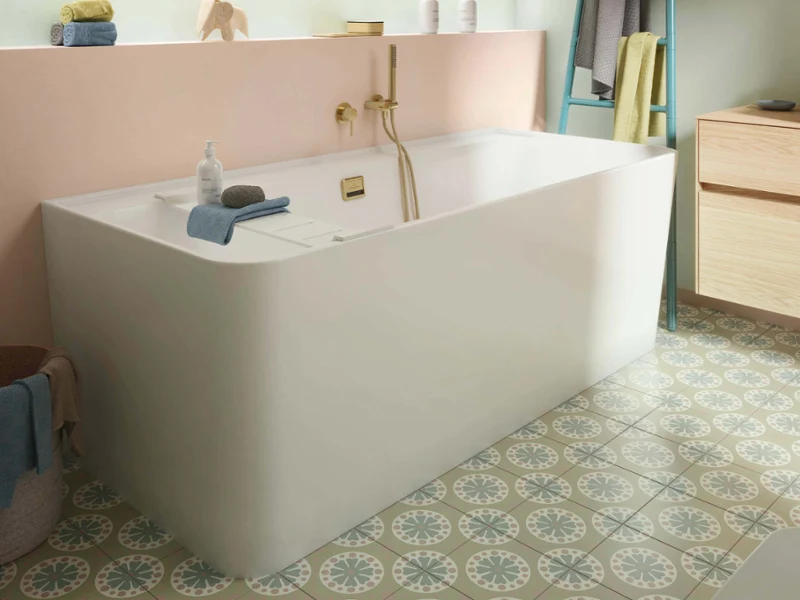 White Collaro bath with gold fittings and pastel decor Playful Collaro bathroom with white bath, gold fittings, and pastel walls. Patterned tiles and soft colors create a fresh, light, and inviting atmosphere.