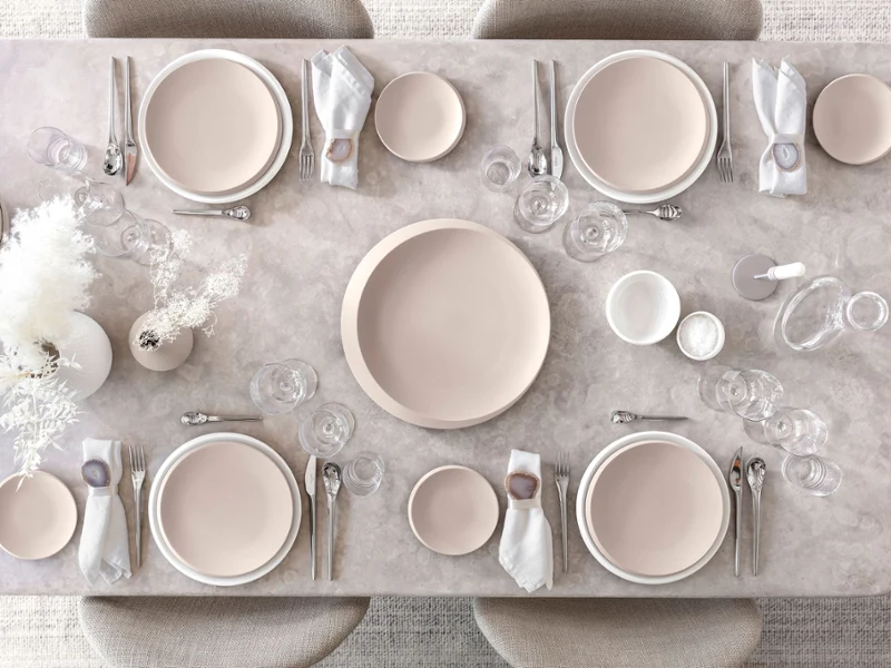 A table set with Villeroy & Boch NewMoon plates in beige and white along with cutlery and glasses.