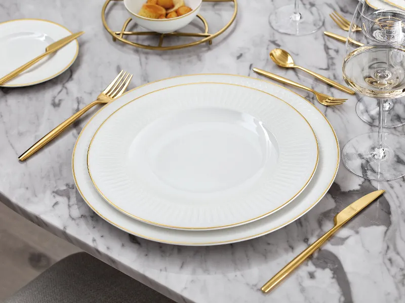 A white and gold Château Septfontaines crockery set on a marble table.