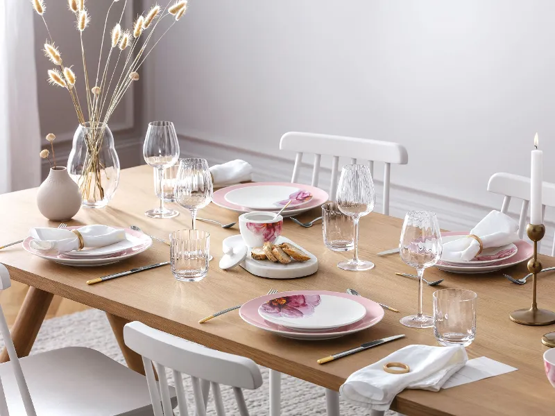 An elegant dining table with modern Rose Garden dinnerware, decorative candles and a Rose Garden vase with pampas grass.