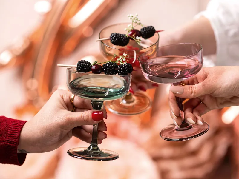 A group of people holding like. champagne coupes decorated with berries.