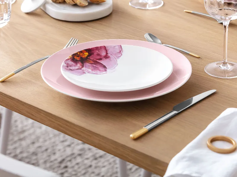 A minimalist dining table with elegant floral-patterned Rose Garden plates, complemented by modern, gold Ella cutlery.