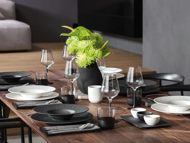 Ein stilvoll gedeckter Tisch mit Geschirr aus der Manufacture Kollektion in Schwarz und Weiß, ergänzt durch eine schwarze Vase.