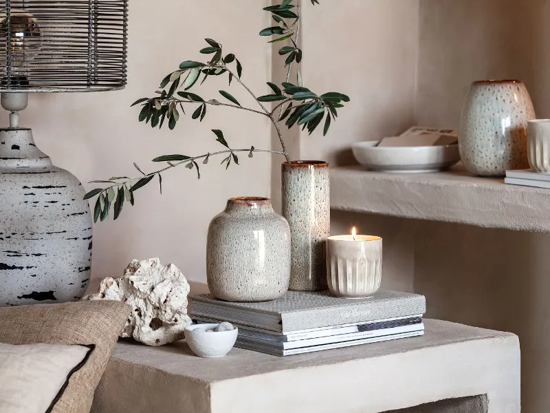 A living room with Perlemor scented candles, Lave vases and books on a shelf.