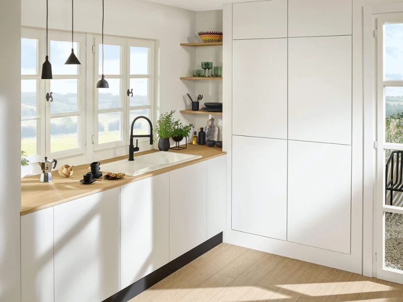 Black Linara kitchen tap in a white kitchen Bright, modern kitchen with wooden worktops, white cabinets and views of the countryside.