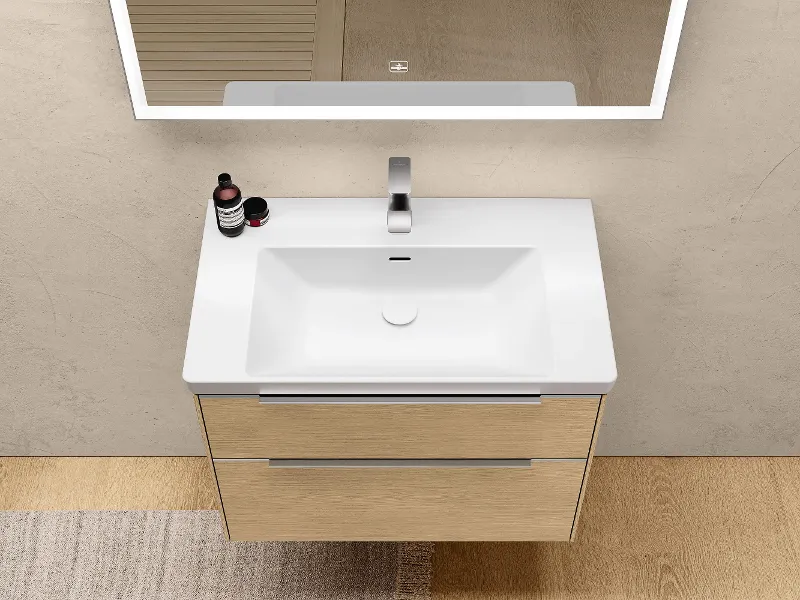 A white Subway 3.0 bathroom washbasin with a brown vanity unit and tap.