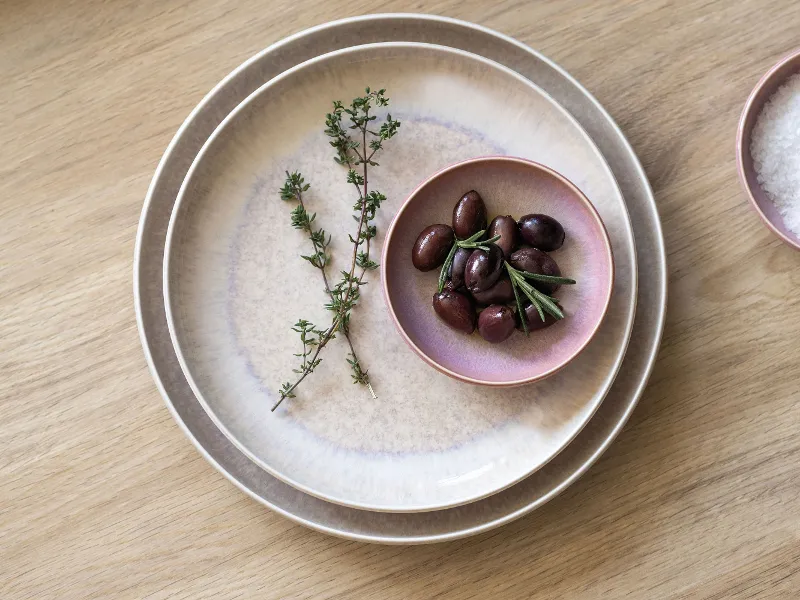 Perlemor plate and dip bowl with olives and salt on a wooden table.