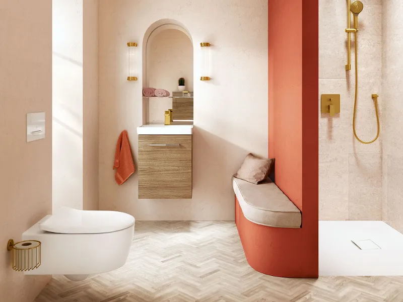 A bathroom with an orange wall and a white washbasin and white toilet from the Avento collection by Villeroy & Boch.