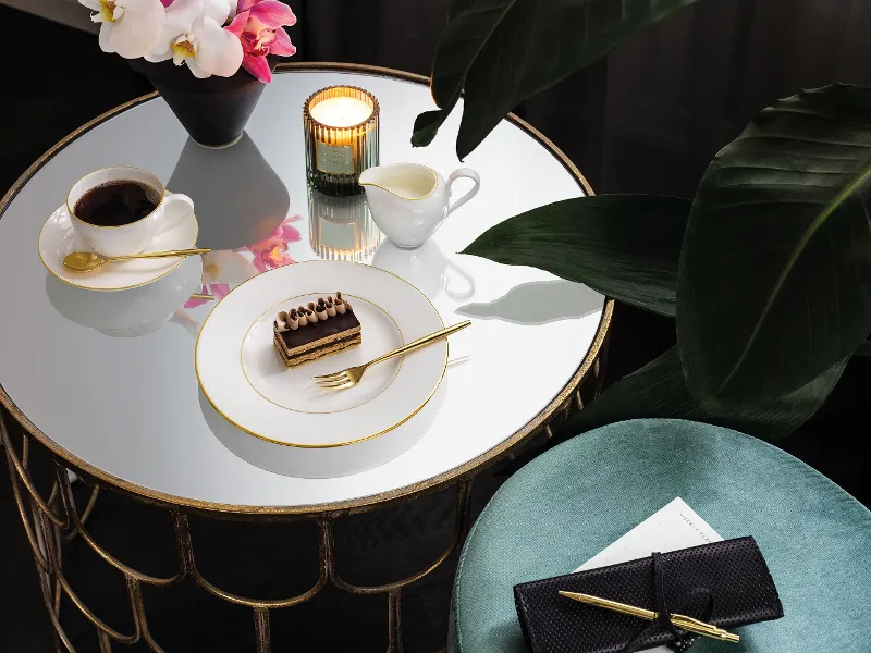 Eleganter Tisch mit Villeroy & Boch Geschirr aus der Kollektion Anmut Eleganter Tisch mit Villeroy & Boch Geschirr aus der Kollektion Anmut, Kaffee, Dessert und Pflanzen im Hintergrund.