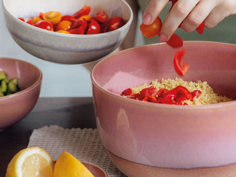 Eine Frau bereitet einen Couscous-Salat in einer Perlemor Salatschüssel von like. by Villeroy & Boch zu.