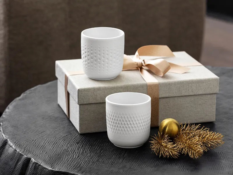 Two Collier scented candles in a gift box with a gold bow and a small gold pine cone decoration.