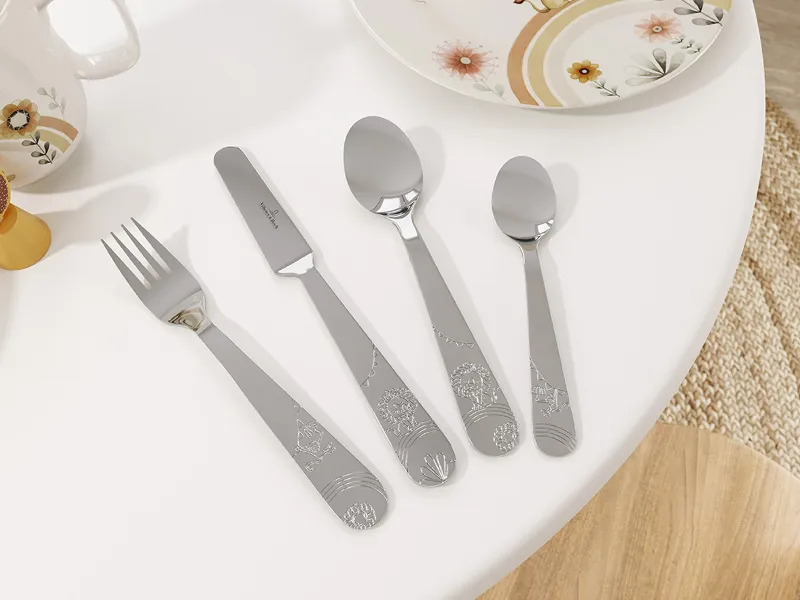 A set of children’s stainless steel cutlery from the Boho Kids collection with a playful pattern, neatly arranged next to a porcelain plate with a playful animal pattern.