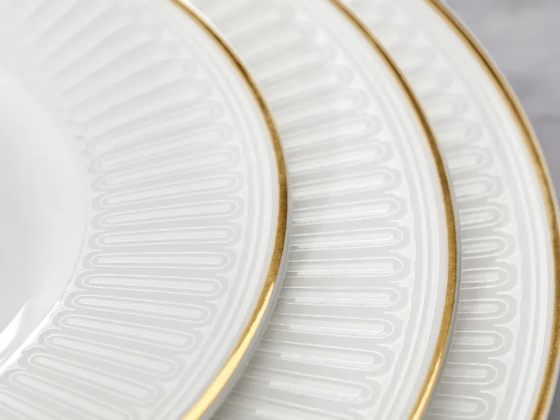 Three interlocking white porcelain plates with gold rims and intricate patterns.