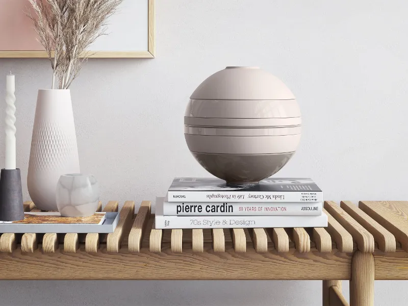 A Villeroy & Boch beige La Boule on a wooden table beside a vase and books.