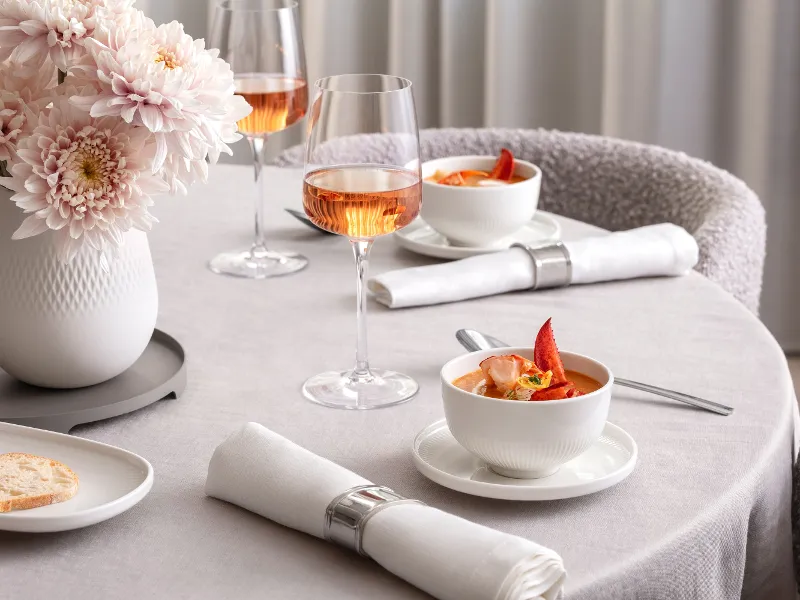 Two filled wine glasses standing on a table. Afina collection.
