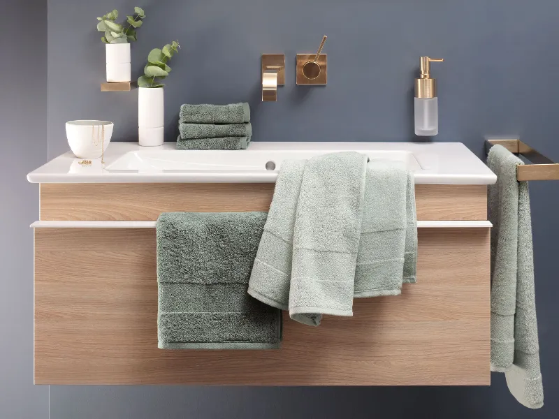 A washbasin with green towels from the One collection by Villeroy & Boch and a mirror.