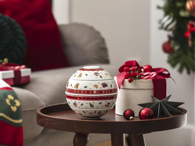 toys delight la petite boule with gift box La petite boule, a decorated ceramic bowl, stands on a wooden table next to a gift box and festive Christmas decorations.