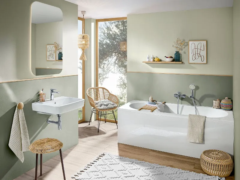 A bathroom with green walls, wooden furniture and a white O.novo bath and washbasin.