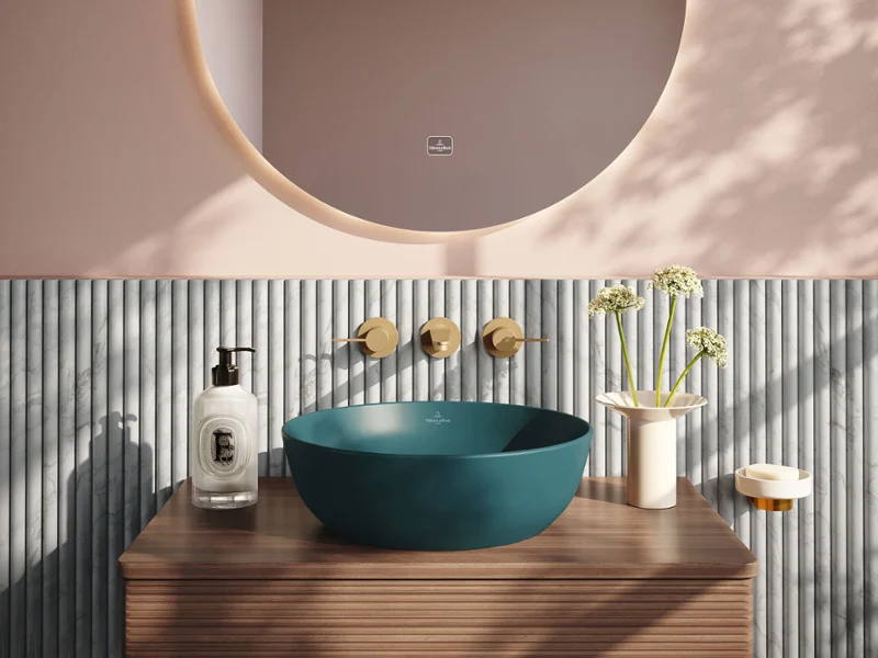 Modern bathroom with a round mirror, two globe lamps, a blue washbasin, a striped wall, and a wooden countertop with decorative details.
