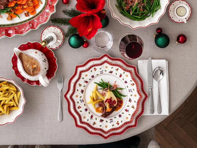 A festively laid table A festively laid table with decorated plates, wine glasses and a centrepiece of red flowers and ornaments.