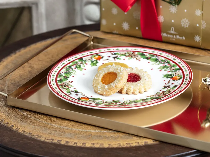 Christmas biscuits on a festive Winter Bakery Delight plate with a gift in the background.