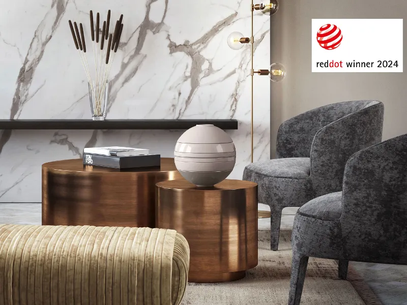 Beżowa La Boule stoi na małym drewnianym stoliku w salonie. W prawym górnym rogu znajduje się odznaka reddot Award 2024