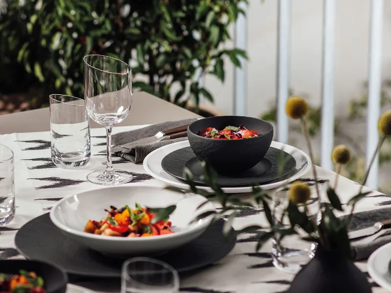 A table set with Villeroy & Boch black Manufacture and white NewMoon plates and bowls.